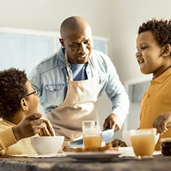 Man and two boys eat breakfast